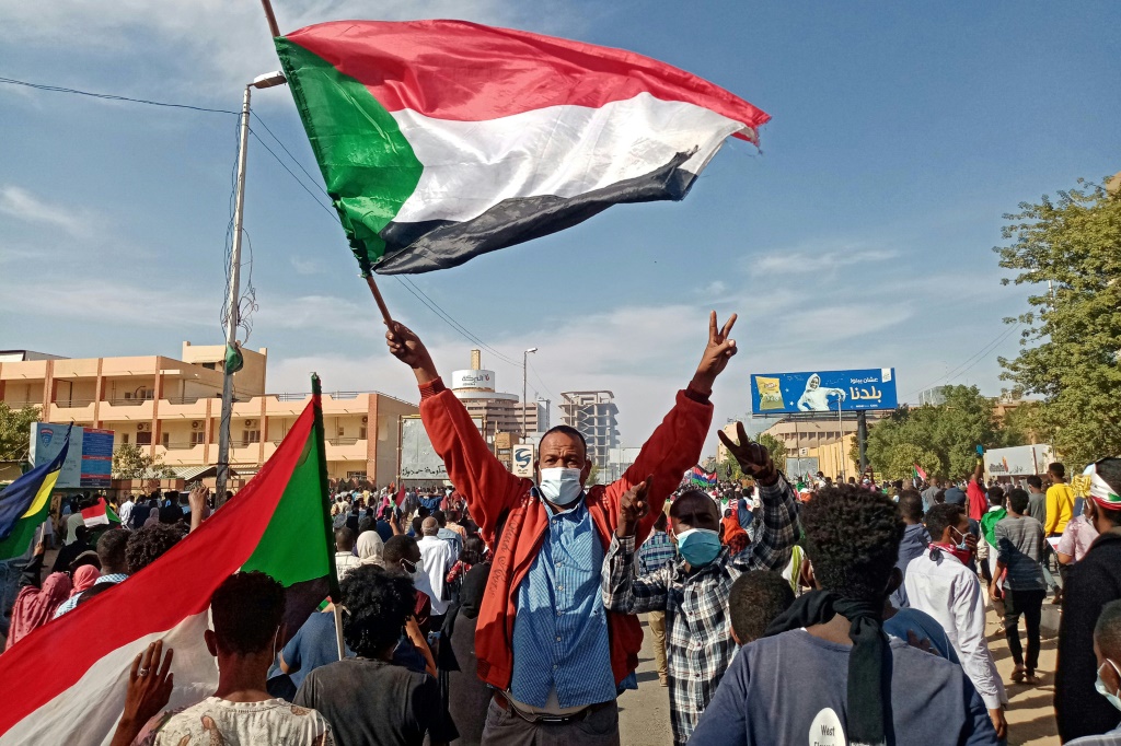 متظاهر سوداني يلوح بالعلم الوطني خلال مسيرة لإحياء ذكرى مرور ثلاث سنوات على بدء المظاهرات الجماهيرية التي أدت إلى الإطاحة بالرئيس عمر البشير في 19 ديسمبر (أ ف ب)