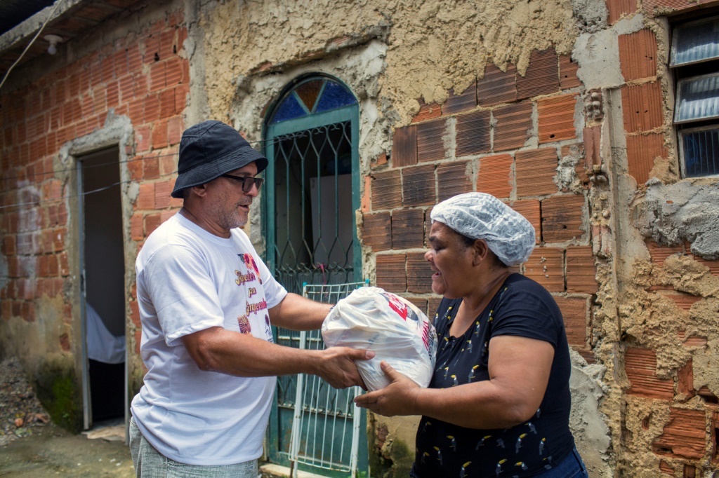 ريتا ماريا دي سوزا (59 عاما) تتلقى مساعدات غذائية من متطوع في إطار عملية "ناتال سيم فومي" (ا ف ب)