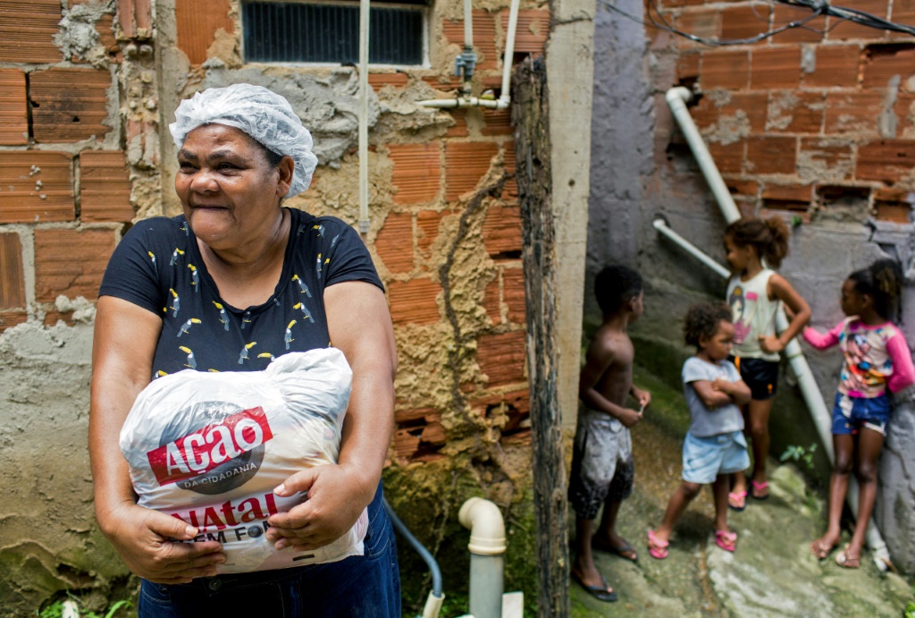 ريتا ماريا دي سوزا تحمل مساعدات غذائية تلقتها في إطار حملة "ناتال سيم فومي" (ا ف ب)