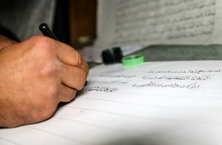 العراقي جمال رسول حسين يتمرن على كتابة الخط العربي في منزله بمدينة رانية في كردستان العراق في 17 كانون الأول/ديسمبر 2021 (ا ف ب)
