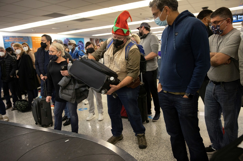 رجل يعتمر قبعة شخصية ميلادية يأخذ حقيبته في مطار ميامي قي فلوريدا في 23 ديسمبر 2021 (ا ف ب)