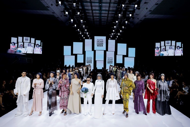 كونغ تري (في الوسط) بين مجموعة عارضات يرتدين تصاميمه في نهاية عرض خلال أسبوع الموضة الفيتنامي الدولي في مدينة هوشي منه في 3 كانون الأول/ديسمبر 2020 (ا ف ب)