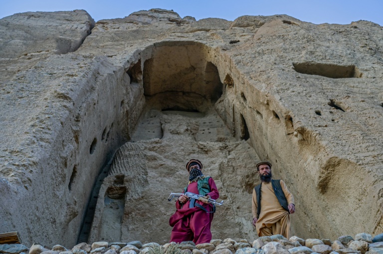 مقاتلو طالبان يقفون في حراسة أمام الموقع الذي كان يضم في يوم من الأيام تمثالًا لبوذا نسفه الإسلاميون في عام 2001 (أ ف ب)