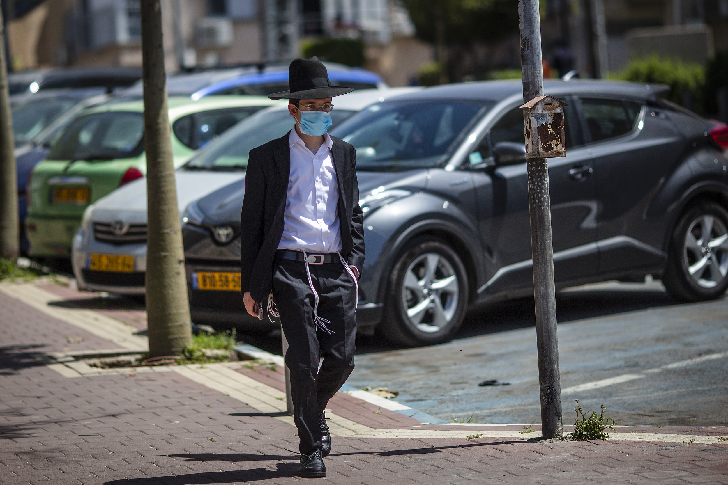 بني براك: رجل يرتدي قناعا جراحيا يسير في الشارع قبل شابات وسط تفشي الفيروس التاجي(ا ف ب)