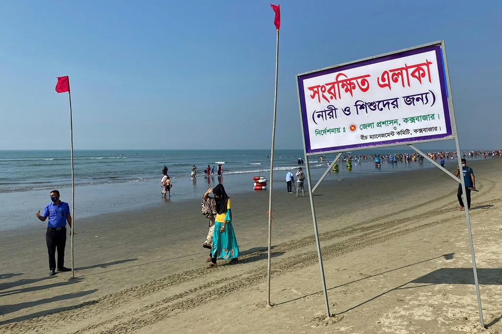 صورة التقطت في 29 كانون الأول/ديسمبر 2021 على شاطئ كوكس بيتش في بنغلادش وبدا فيها عدد من المارة أمام لافتة كُتب عليها "منطقة محصورة بالنساء والأطفال" (أ ف ب)