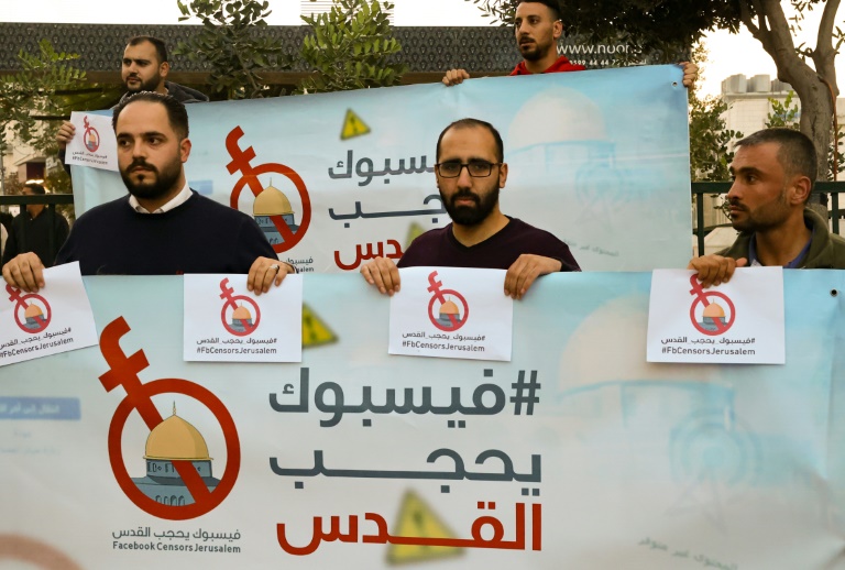 ناشطون وصحافيون فلسطينيون يرفعون لافتات خلال احتجاجات على ما يعتبرونه رقابة تمارسها فيسبوك على المحتويات الفلسطينية في مدينة الخليل في الضفة الغربية المحتلة في 24 تشرين الثاني/نوفمبر 2021(ا ف ب)