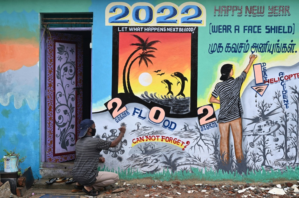 فنان يضع اللمسات الأخيرة على لوحة جدارية عن العام الجديد في 20 كانون الأول/ديسمبر 2021 في شيناي في الهند (أ ف ب)   