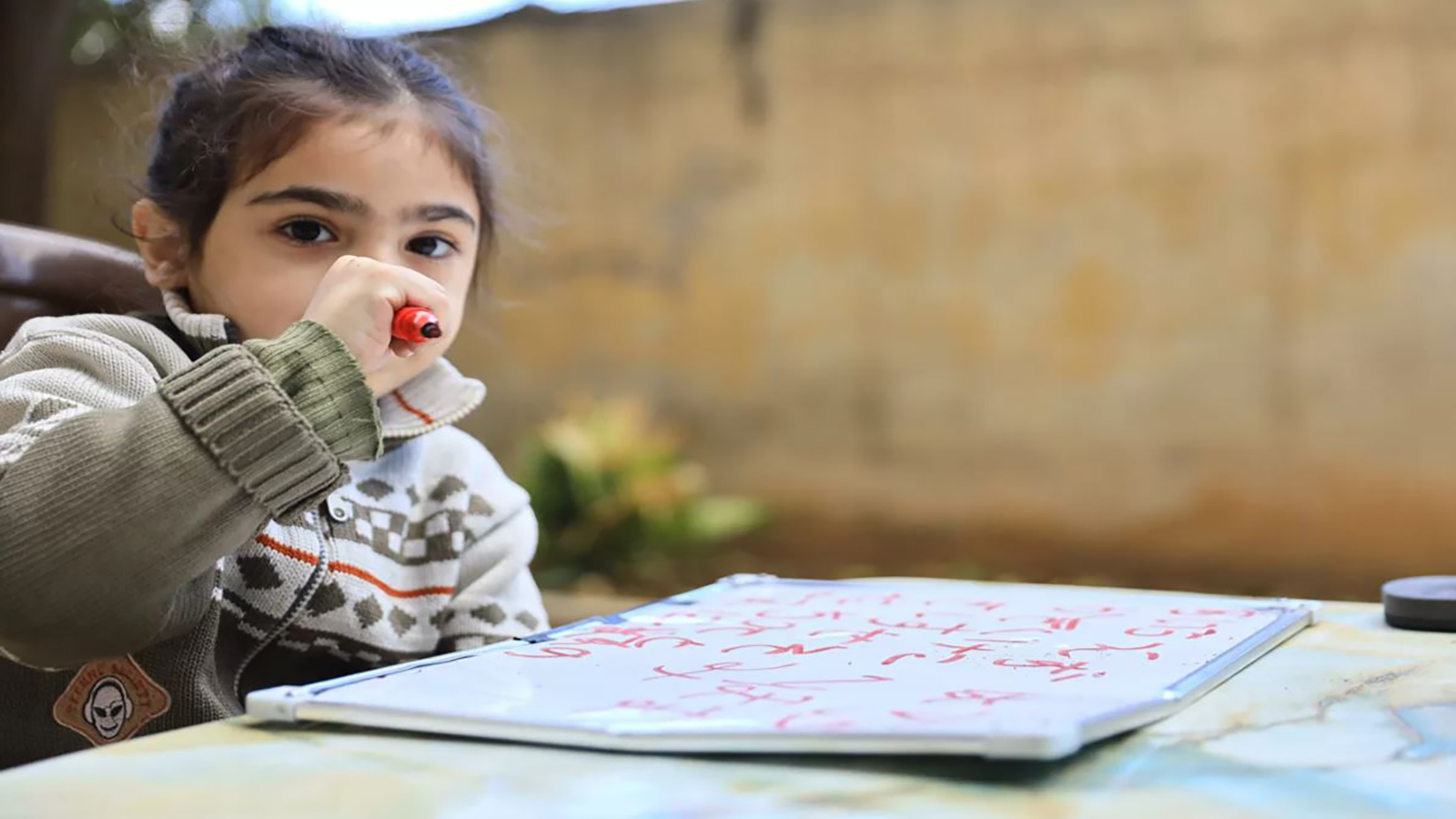 تسلح الطفل السوري ذو الخمسة أعوام بقلم ملون ونجح في كتابة أول كلمة في حياته حين كان عمره سنتين فقط (التواصل الاجتماعي)