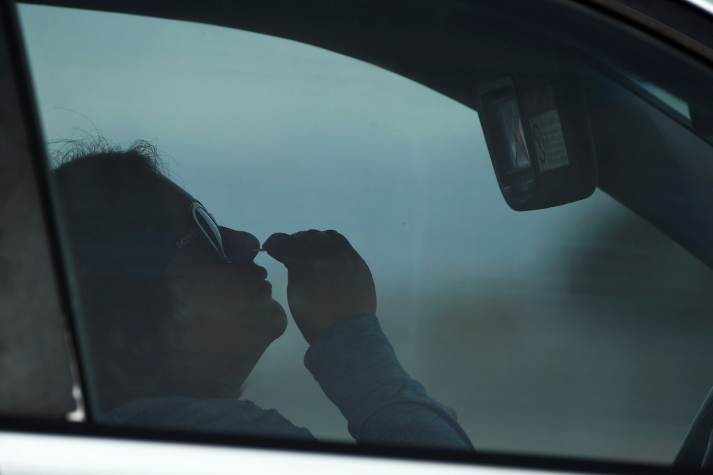 امرأة تأخذ مسحة لفحص كوفيد-19 في منشأة للفحوص داخل مرآب للسيارات في منطقة لونغ بيتش بولاية كاليفورنيا الأميركية في 10 كانون الثاني/يناير 2022(ا ف ب)