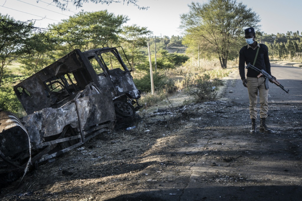 شرطي اثيوبي ينظر الى شاحنة عسكرية مدمرة في منطقة امهرة باثيوبيا في 10 كانون الاول/ديسمبر 2021(ا ف ب)