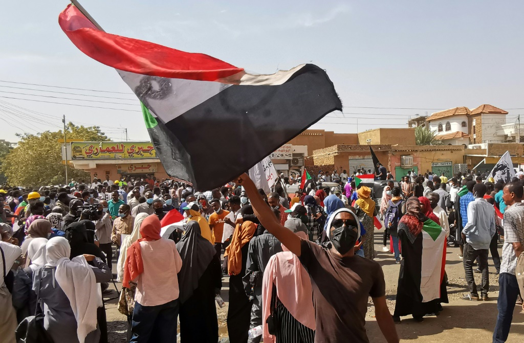    متظاهر سوداني يلوح بالعلم الوطني خلال تظاهرة في الخرطوم في 13 كانون الثاني/يناير 2022 (أ ف ب)