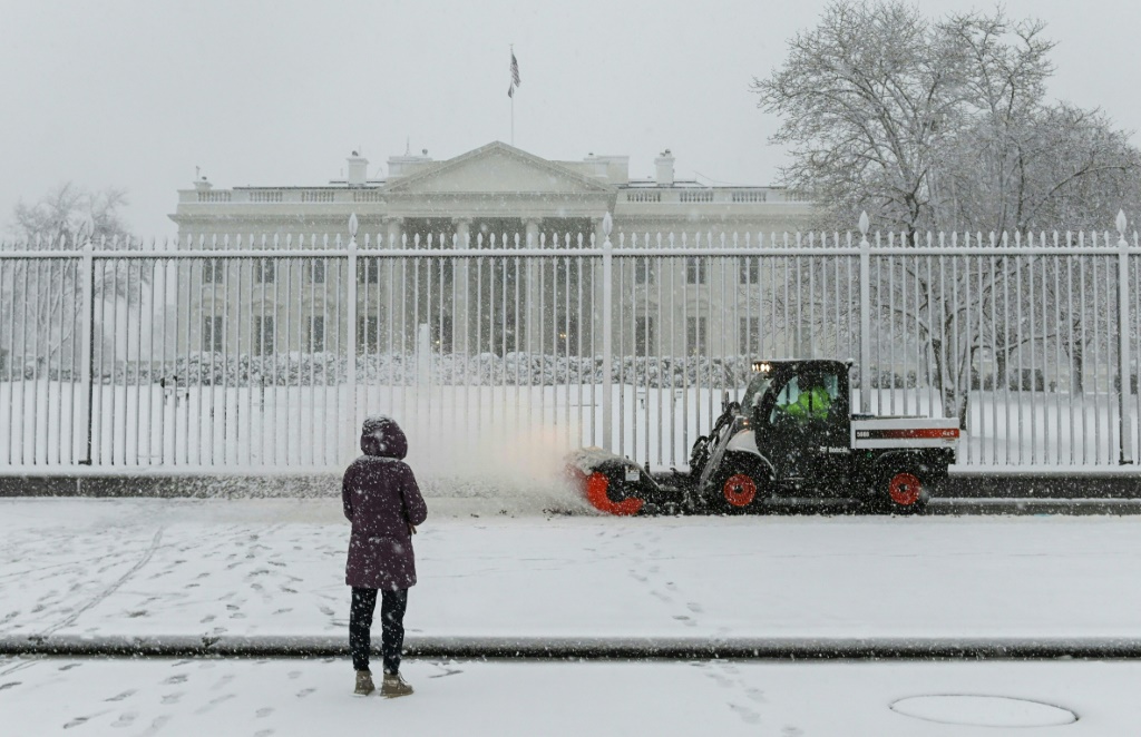 امرأة امام البيت الابيض تحت الثلج في واشنطن في 3  يناير 2022 (ا ف ب)