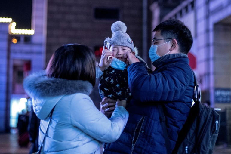 والدان صينيان يضعان كمامة لطفلهما خارج محطة القطارات في بكين في 23 كانون الثاني/يناير 2020(ا ف ب)
