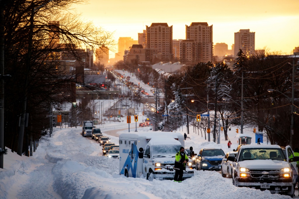 مُسعف ينتظر وصول قاطرة لسحب سيّارة إسعاف علقت في الثلج في تورونتو في مقاطعة أونتاريو في 17 كانون الثاني/يناير 2022(ا ف ب)