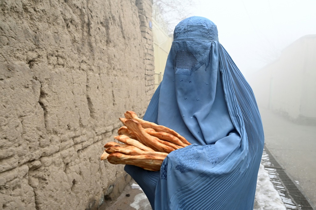 منقبة تحمل خبزا وزعته حملة "أنقذوا الأفغان من الجوع" في كابول في 18 كانون الثاني/يناير 2022(ا ف ب)