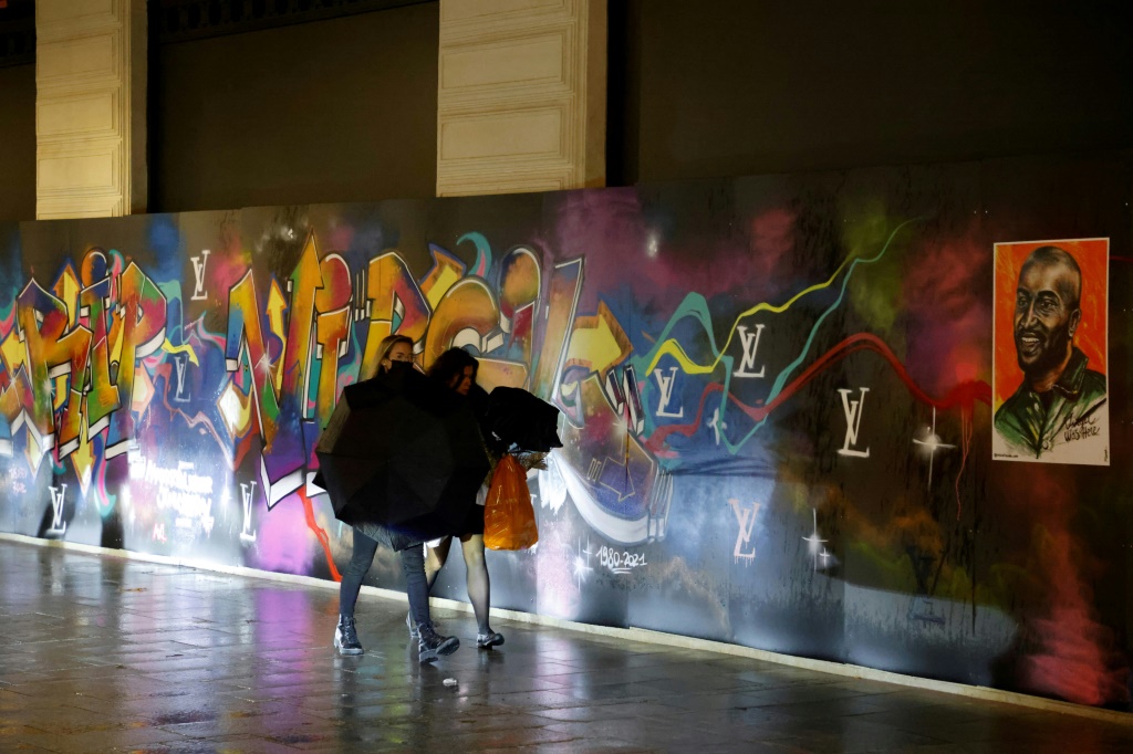 مشاة يسيرون بجانب لوحة فنية قرب مبنى ساماريتين في باريس في 6 كانون الأول/ديسمبر 2021(ا ف ب)