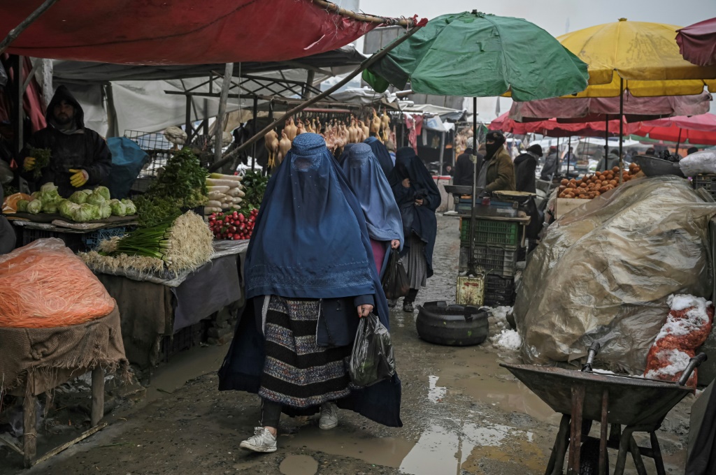نساء يسرن في أحد الأسواق في كابول ، حيث تعمل قيود طالبان الزاحفة على طردهن ببطء من الحياة العامة (ا ف ب)