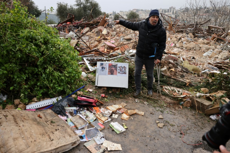  الناشط الفلسطيني محمد أبو الحمص يشير إلى حطام منزل عائلة صالحية الذي هدمته الشرطة الإسرائيلية في حي الشيخ جراح في القدس الشرقية المحتلة في 19 كانون الثاني/يناير 2022(ا ف ب)
