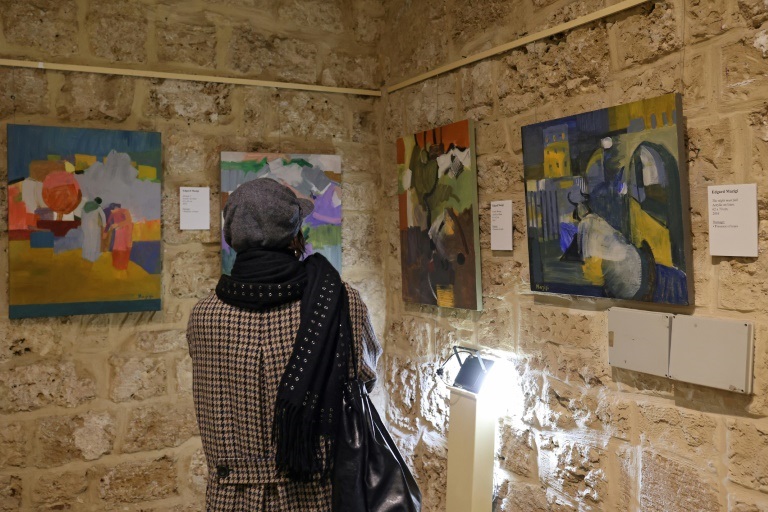 امرأة تنظر إلى لوحة للفنان اللبناني إدغار مازجي خلال افتتاح معرض في بيروت في 20 كانون الثاني/يناير 2022 للوحات مرممة كانت تضررت جراء انفجار مرفأ بيروت (ا ف ب)