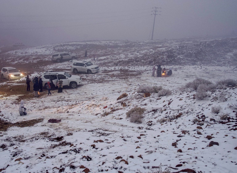 سعوديون يلعبون في الثلوج في جبل اللوز في تبوك في شمال غرب السعودية في 17 كانون الثاني/ينابر 2022 (ا ف ب)