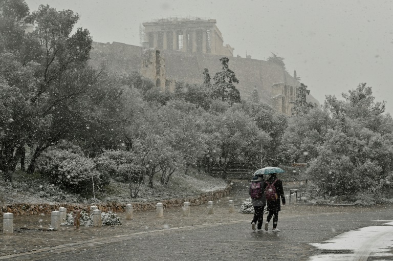 الناس يسيرون بالقرب من الأكروبوليس خلال تساقط الثلوج في وسط أثينا في يناير 24, 2022. يتم إغلاق المدارس في أكبر منطقة أثينا، واليونان exepriences جبهة الطقس البارد مع تساقط الثلوج الكثيفة ودرجات الحرارة المنخفضة جدا(ا ف ب).