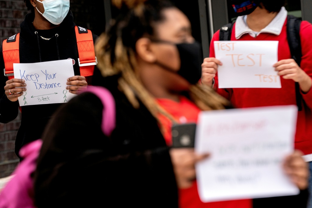 تلامذة ثانويون يحملون لافتات تدعو إلى تعزيز قواعد مكافحة كوفيد-19 في مدرسة في العاصمة الأميركية واشنطن في 25  يناير 2022 (ا ف ب)