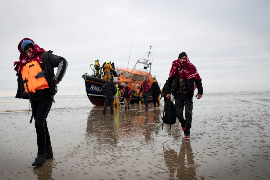 مهاجرون يسيرون باتجاه الشاطئ على الساحل الجنوبي شرقي في انكلترا بعد أن ساعدتهم المؤسسة الملكية الوطنية لقوارب النجاة، في 16 كانون الأول/ديسمبر 2021 (أ ف ب)