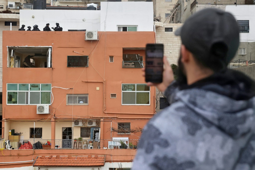 فلسطيني يلتقط صورا لقوات إسرائيلية تقف على سطح منزل عائلة الفلسطيني فادي أبو شخيدم منفذ هجوم بسلاح ناري في البلدة القديمة من القدس الشرقية المحتلة بعد أن قامت القوات الإسرائيلية بتدمير جدران المنزل وإغلاقه في الأول من شباط/فبراير 2022(ا ف ب)