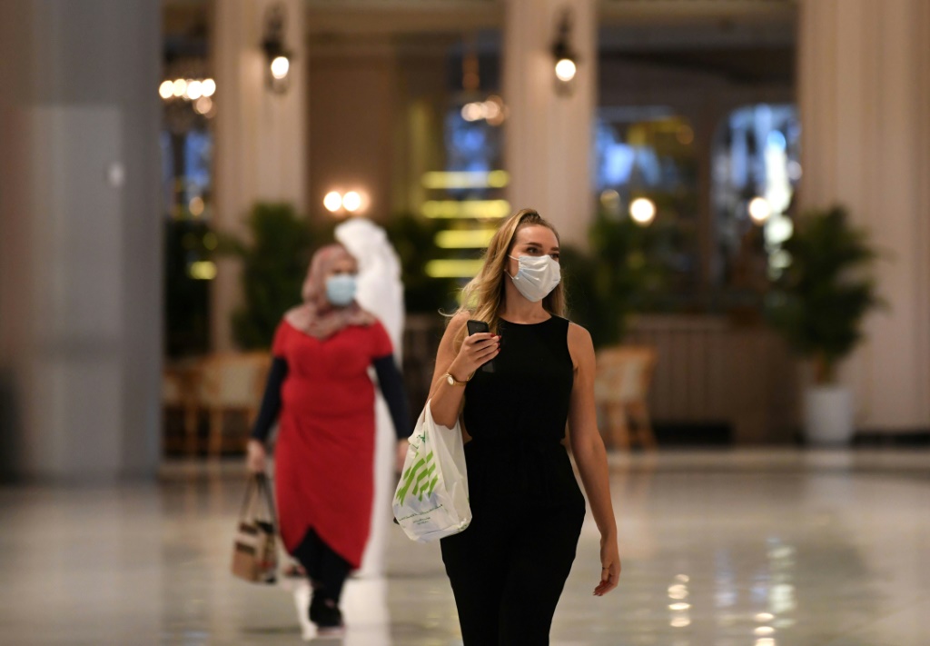 امرأة تضع كمامة وتحمل كيسًا بلاستيكيًا في مركز "دبي مول" للتسوّق في 28 نيسان/أبريل 2020(ا ف ب)