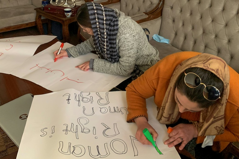 صورة ملتقطة في 15 كانون الثاني/يناير 2022 تظهر نساء أفغانيات يكتبن على لافتات استعدادا لمسيرة لحقوق المرأة في كابول (ا ف ب)