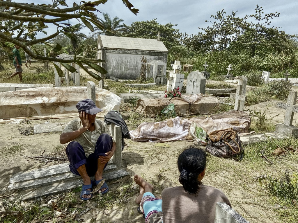 أشخاص ينظرون الى جثث اقربائهم بعدما تسببت الامواج بجرف مقبرة في شرق مدغشقر اثر مرور الاعصار.(ا ف ب)