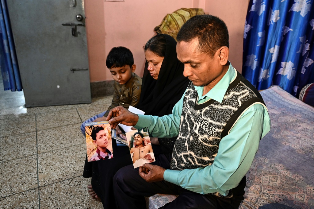 محسن هولدر (يمين) وعائلته يعرضون صور ابنه رقيب البالغ من العمر 14 عامًا والذي توفي أثناء اعتقاله من قبل الشرطة في 2018 (أ ف ب)