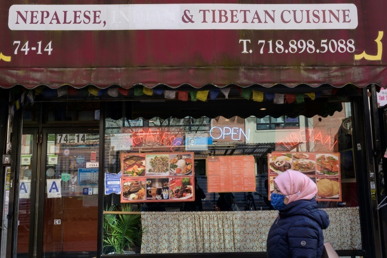 امرأة تمر أمام مطعم يقدم أطعمة نيبالية وتيبتية في حي كوينز في نيويورك في 27 كانون الثاني/يناير 2022 (ا ف ب)