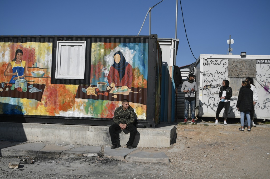 شباب بين حاويات في مخيم إيليوناس للاجئين في أثينا في 9 شباط/فبراير 2022(ا ف ب)