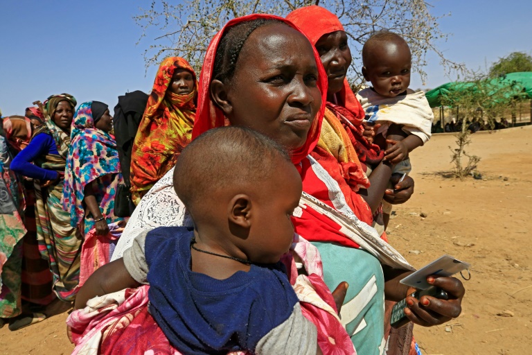 نساء سودانيات ينتظرن في 1 فبراير/شباط 2021 شاحنات المساعدات التابعة لبرنامج الأغذية العالمي في مخيم أوتاش في دارفور للنازحين داخليا(ا ف ب)
