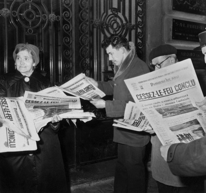 أشخاص يقرأون الصحف قرب كشك في باريس في 18 آذار/مارس 1962 بعد الإعلان عن وقف إطلاق نار بين فرنسا والجزائر (أ ف ب)