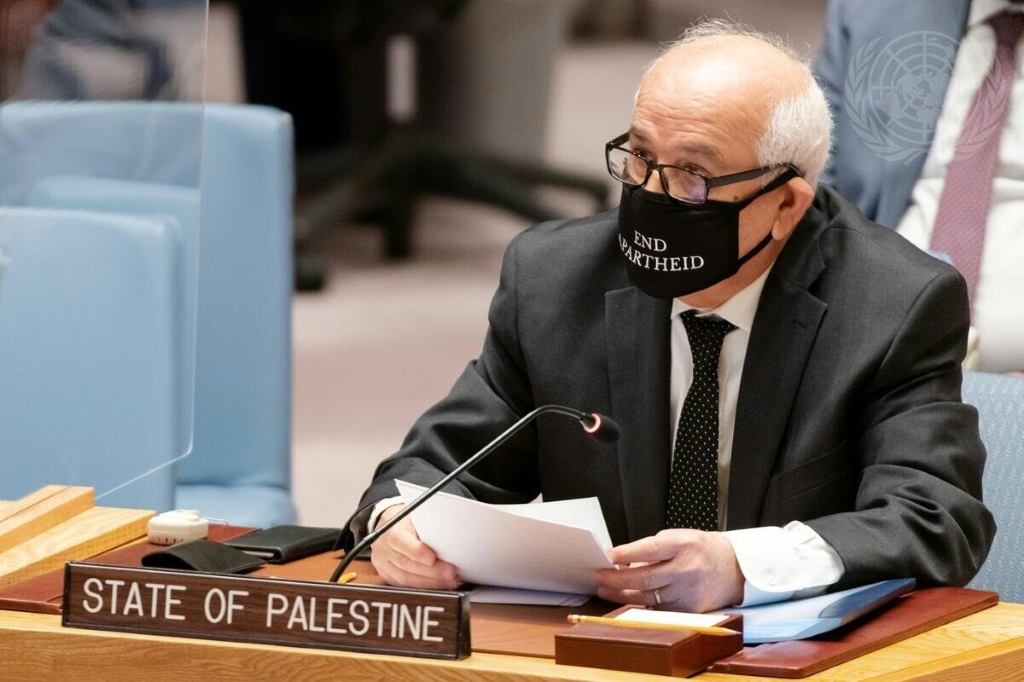 السفير الفلسطيني لدى الأمم المتحدة رياض منصور يلقي خطابًا أمام مجلس الأمن الدولي في 23 شباط/فبراير 2022 في نيويورك، واضعًا كمامة مكتب عليها بالانكليزية "إنهاء الفصل العنصري"(ا ف ب)