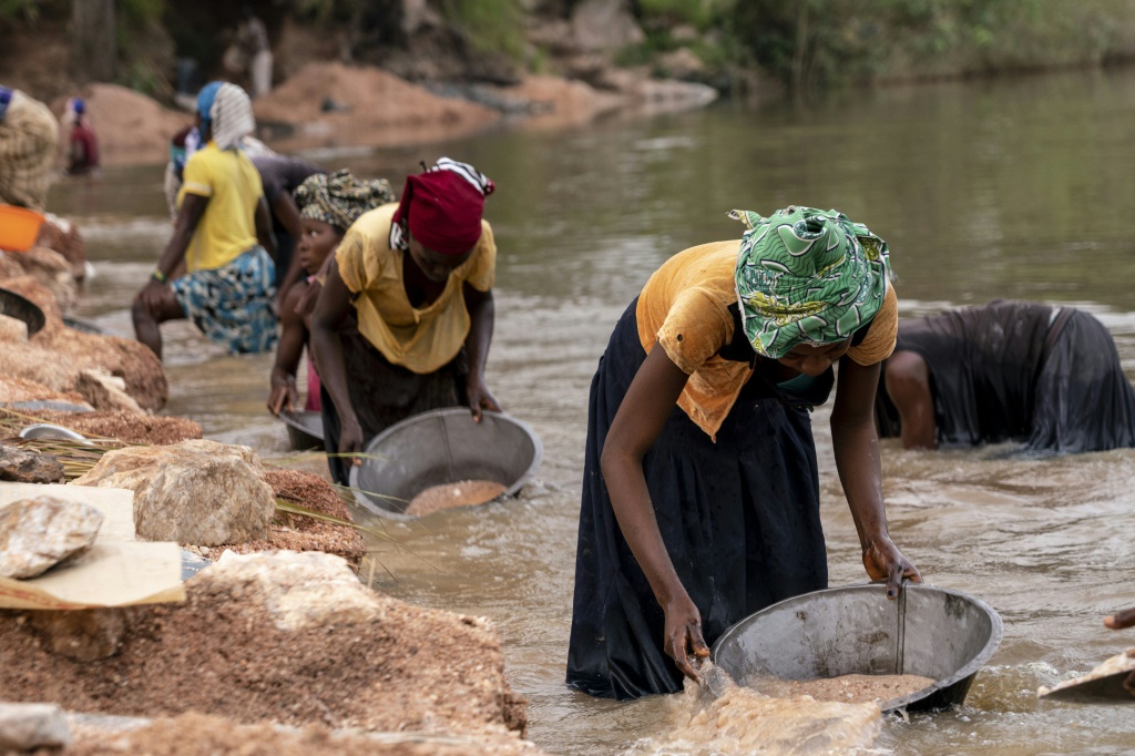 تغسل النساء الغنيمة في مياه النهر ، على أمل العثور على شذرات من حجر القصدير (أ ف ب)
