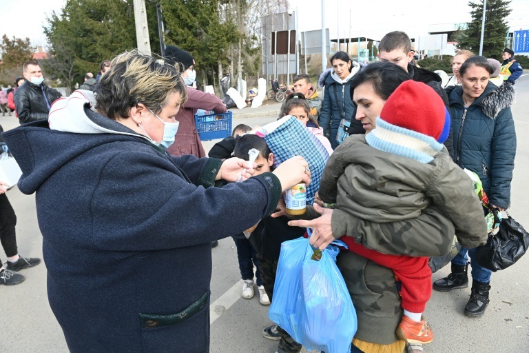 سيدة تقدم الطعام إلى لاجئة أوكرانية تحمل طفلها عند معبر تيزابيتش الحدودي في المجر، في 27 شباط/فبراير 2022 (ا ف ب)