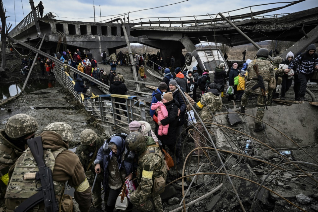 سكان من ايربين شمال غرب العاصمة الاوكرانية كييف يفرون عبر جسر مدمر خلال عمليات قصف روسية في 05 آذار/مارس 2022(ا ف ب)