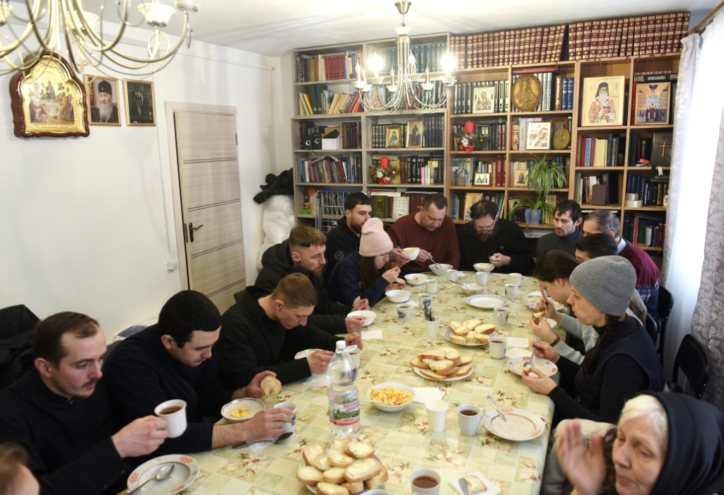 اللاجئون يتناولون وجبة الإفطار في غرفة مليئة بالكتب والأيقونات (أ ف ب)   