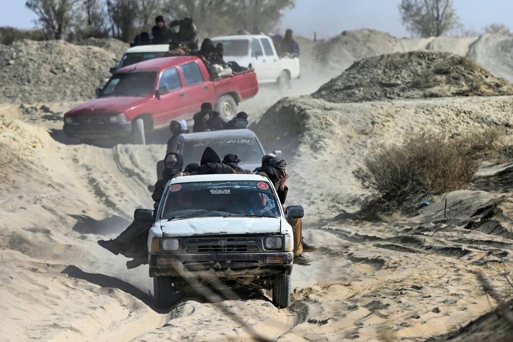 في صورة ملتقطة في 17 شباط/فبراير 2022 تظهر شاحنات صغيرة تنقل مهاجرين عبر طريق صحراوي عند الحدود الأفغانية-الإيرانية في نمروز (أ ف ب)