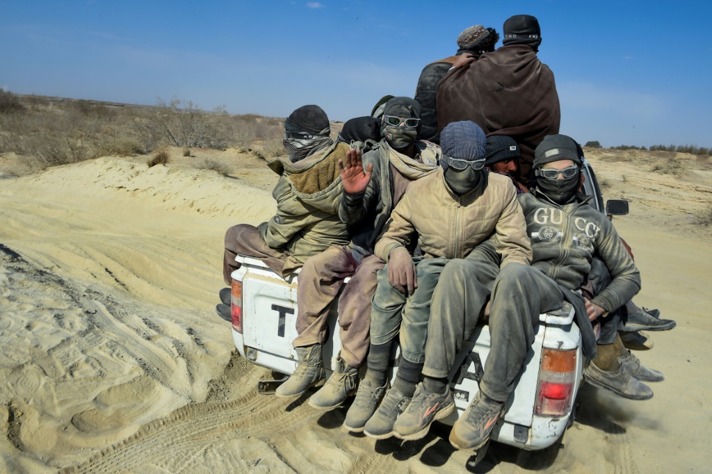 صورة ملتقطة في 17 شباط/فبراير 2022 تظهر مهاجرين أفغانا في مؤخر شاحنة صغيرة في الطريق الصحراوي المؤدي إلى الحدود الأفغانية-الإيرانية في نمروز (أ ف ب)