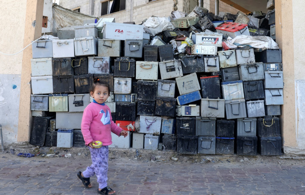 فتاة تمرّ قرب مكب بطاريات للتدوير في جنوب قطاع غزة في 14 شباط/فبراير 2022 (أ ف ب)
