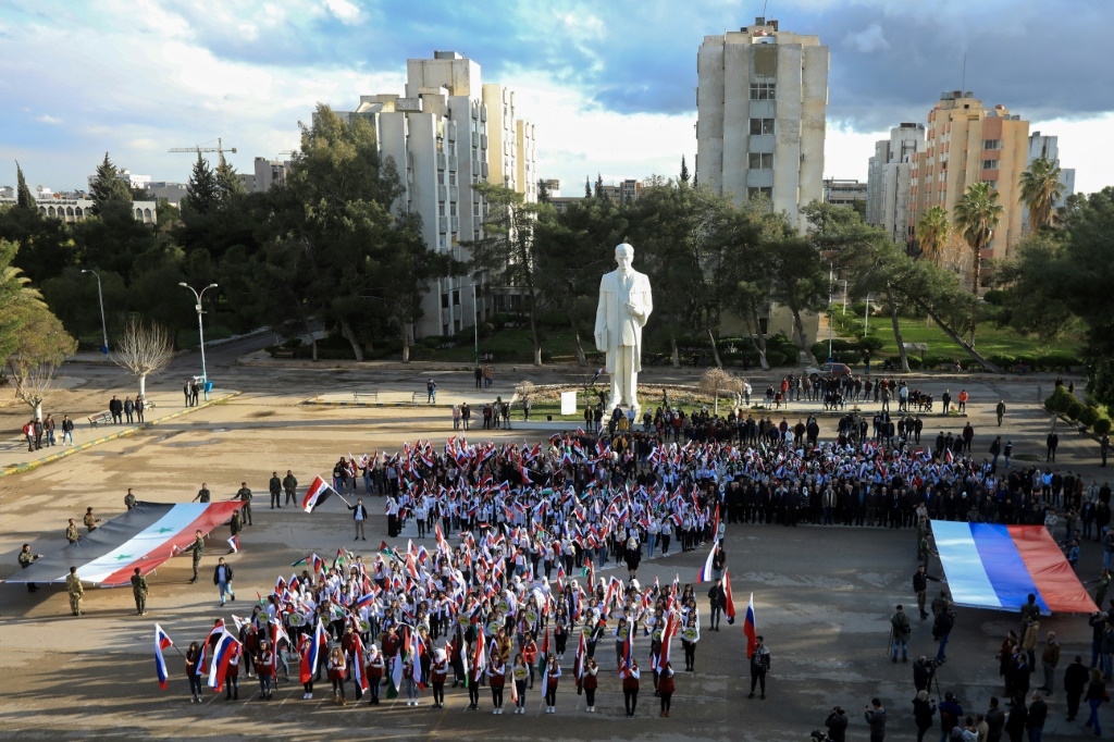 طلاب يلوحون بالأعلام أثناء تجمعهم دعماً لروسيا في جامعة دمشق بالعاصمة السورية في 9 آذار 2022 (أ ف ب)   