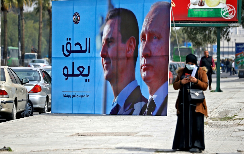    لافتة تصور الرئيس السوري بشار الأسد والرئيس الروسي فلاديمير بوتين وكتب عليها "العدالة تسود" ، على طول طريق سريع في العاصمة السورية دمشق ، في 8 آذار 2022 (أ ف ب)