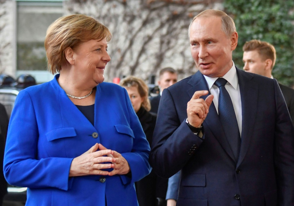 المستشارة الألمانية السابقة أنغيلا ميركل والرئيس الروسي فلاديمير بوتين عند وصوله إلى قمة السلام حول ليبيا في برلين في ألمانيا في 19 كانون الثاني/يناير 2020 (أ ف ب)