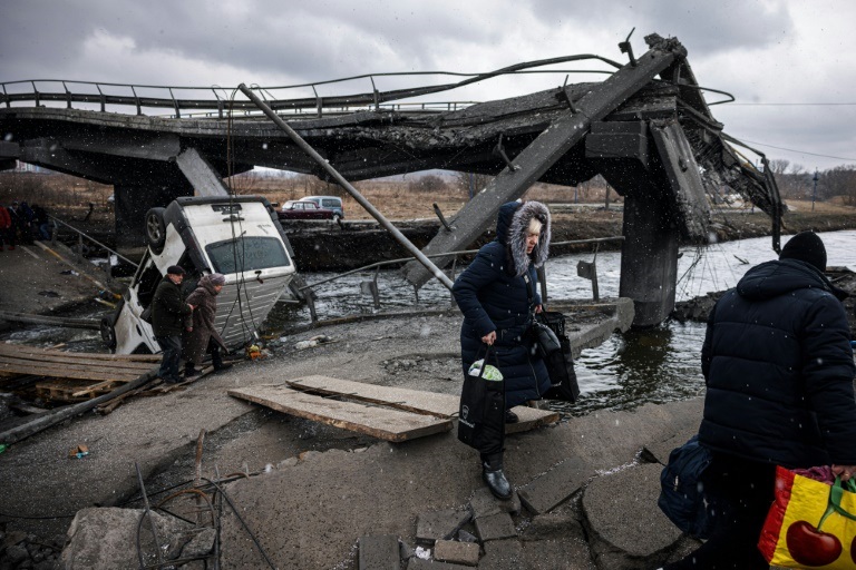 أوكرانيون يفرون من مدينة إربين في شمال غرب كييف ويعبرون نهرًا قرب جسر مدمّر في 13 آذار/مارس 2022 (ا ف ب)