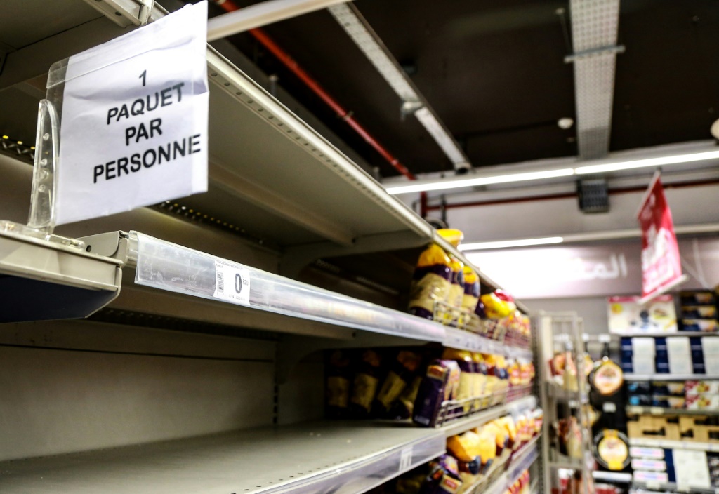 لافتة على أرفف فارغة تقريبًا من الخبز والأطعمة الأخرى المصنوعة من القمح تقول: "كيس واحد لكل شخص" في متجر بالعاصمة التونسية في 13 آذار/مارس 2022 (أ ف ب)   