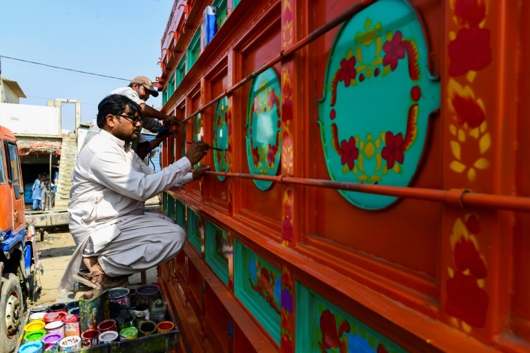 الفنان الباكستاني حيدر علي يلوّن شاحنة ليحولها قطعة فنية في كراتشي في 28 شباط/فبراير 2022 (ا ف ب)